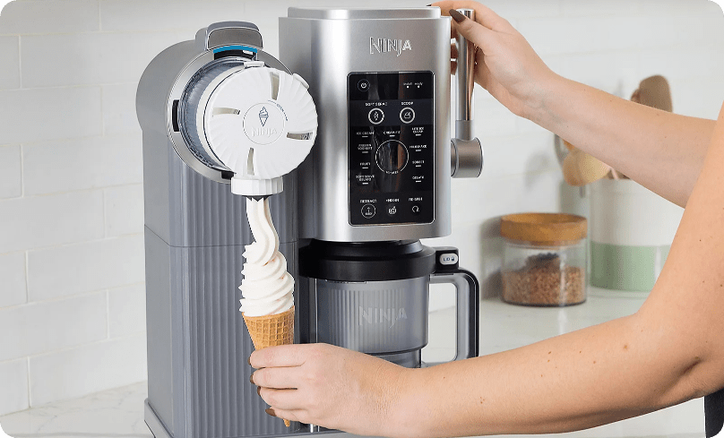 Γυναίκα που φτιάχνει μαλακό παγωτό βανίλιας σε κώνο με την παγωτομηχανή Ninja σε λευκή κουζίνα